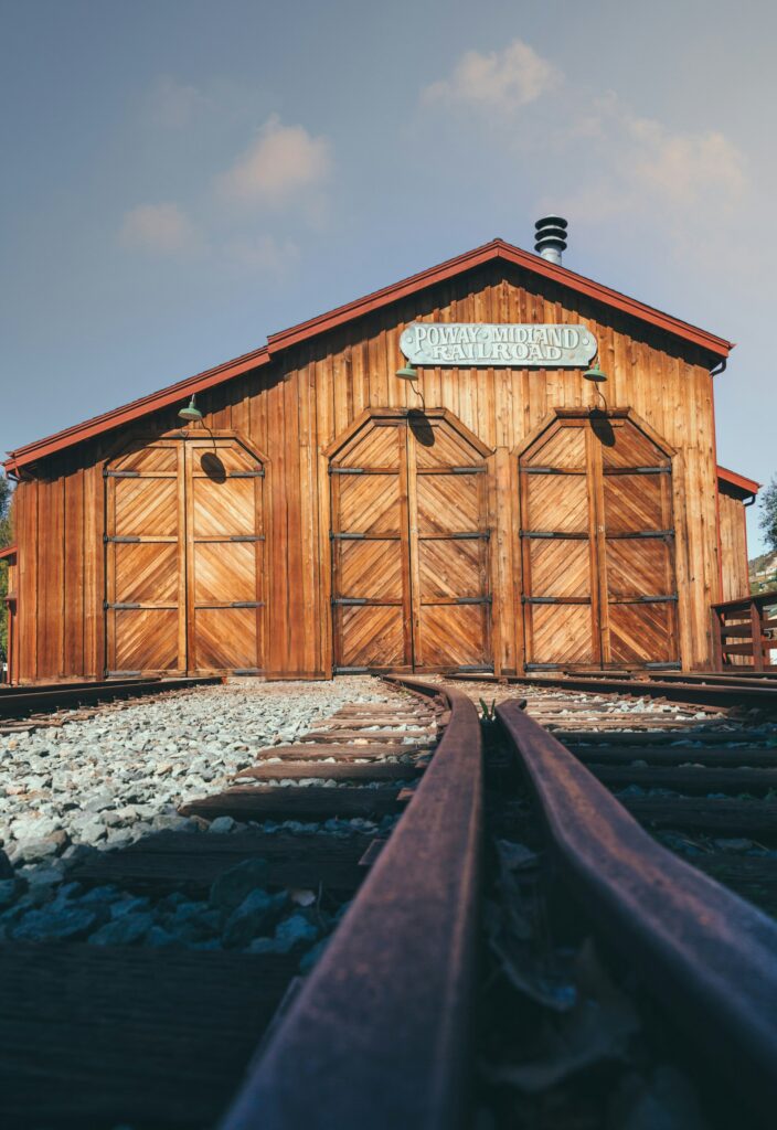 A close-up view of the Poway Midland Railroad station building, showcasing the wooden structure and railroad tracks leading toward it.