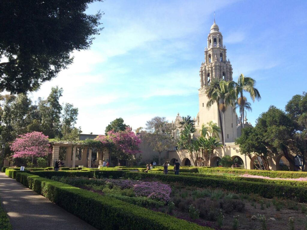 A garden with blooming flowers and a historic tower in the background.