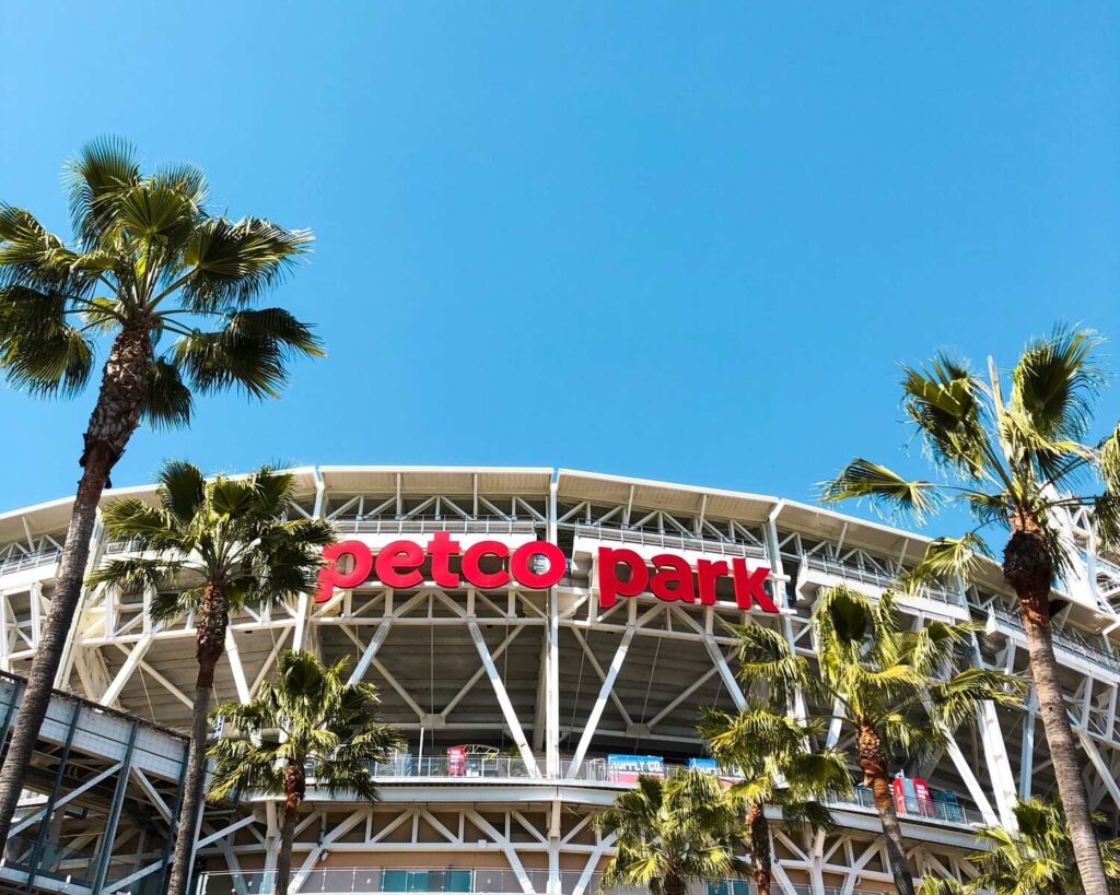 The exterior of Petco Park stadium surrounded by palm trees under a clear blue sky.