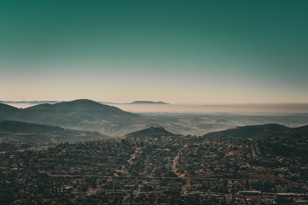 A scenic view of El Cajon, California, showing a sprawling suburban area surrounded by rolling hills under a clear sky.