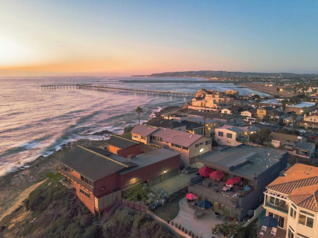 Aerial view of houses along the coastline with the ocean at sunset